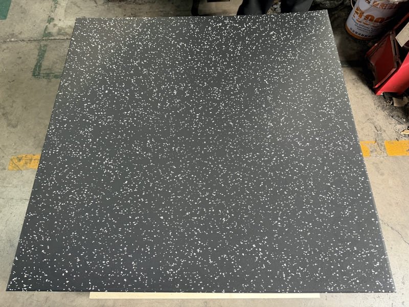 Przekrój poprzeczny czarnej gumowej podłogi gimnastycznej o wysokiej gęstości pokazujący strukturę drobnych granulek